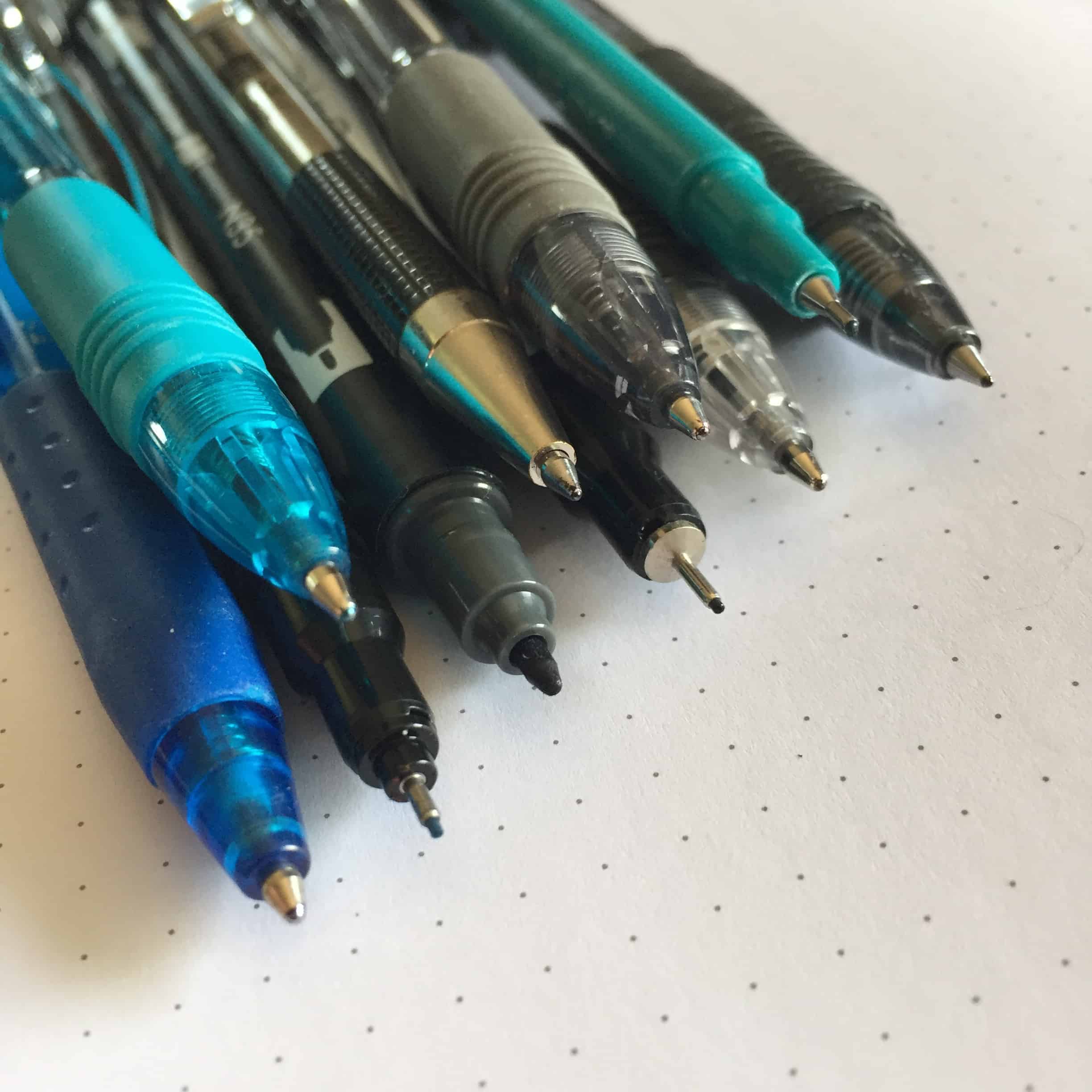 photo of the tips of several pens laid out evenly on top of a sheet of dot grid paper