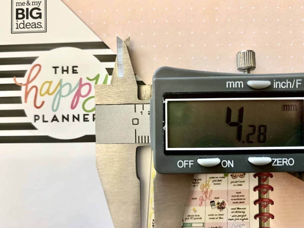 A photograph of The Happy Planner dot grid paper with calipers measuring spacing between dots in millimeters